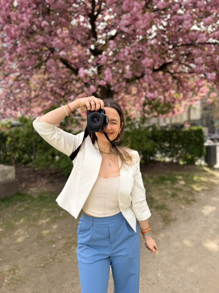 Woman with camera in front of blooming cherry tree